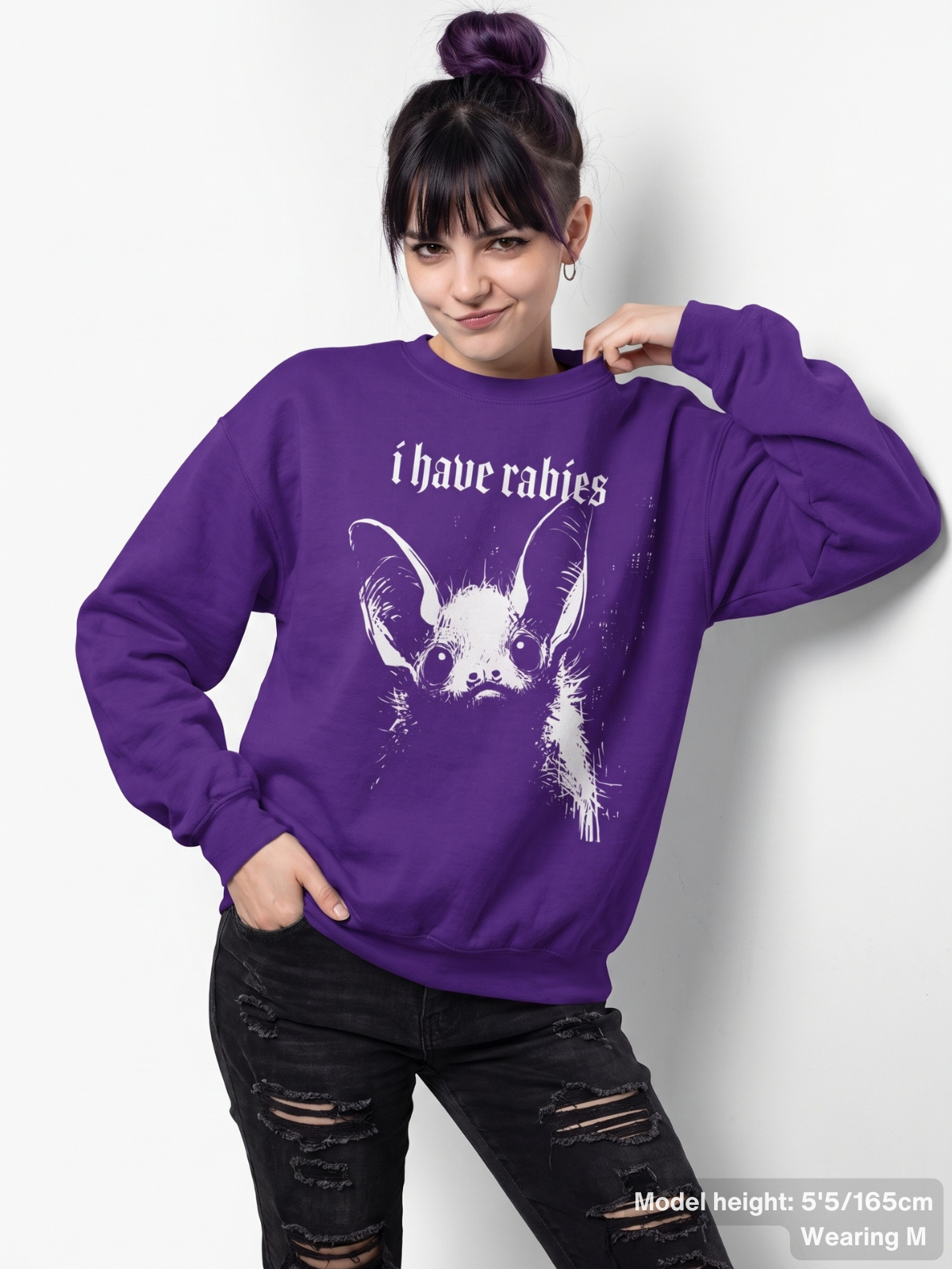 Female model wearing the KAMIOJI I Have Rabies graphic sweatshirt featuring a distressed gothic bat design | Colour: Purple