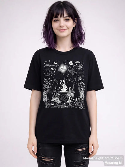 T shirt featuring a detailed celestial illustration of cats gathered around a cauldron, surrounded by stars, moons, plants, and animals. KAMIOJI. | Colour: Black