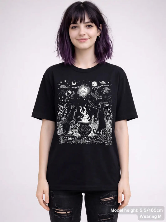 T shirt featuring a detailed celestial illustration of cats gathered around a cauldron, surrounded by stars, moons, plants, and animals. KAMIOJI. | Colour: Black