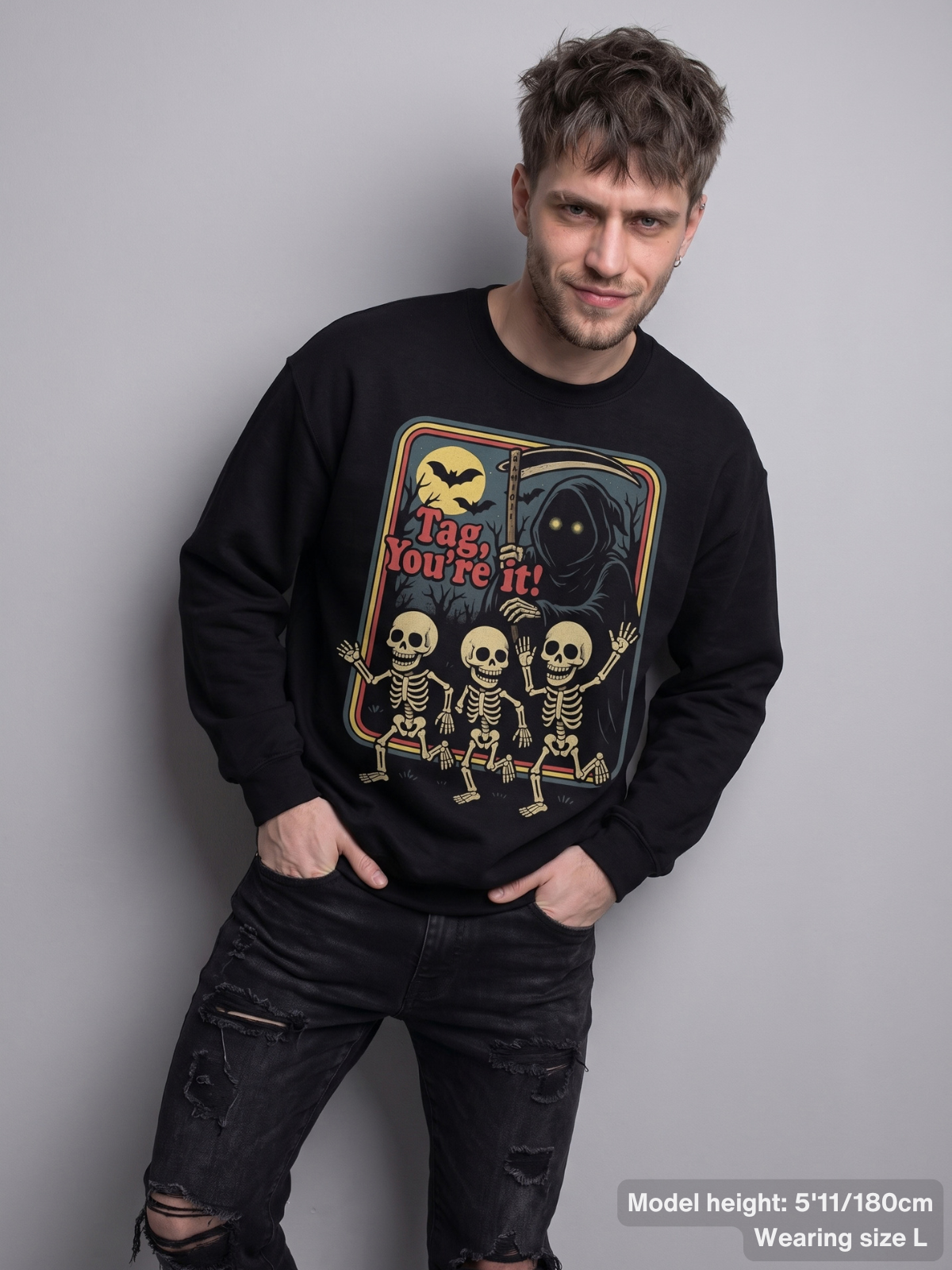 Male model wearing the KAMIOJI Tag You’re It sweatshirt featuring a vintage skeleton Halloween graphic | Colour: Black