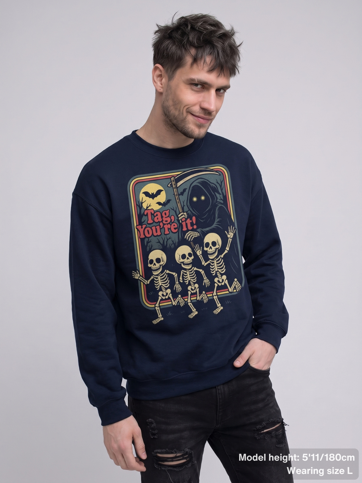Male model wearing the KAMIOJI Tag You’re It sweatshirt featuring a vintage skeleton Halloween graphic | Colour: Navy