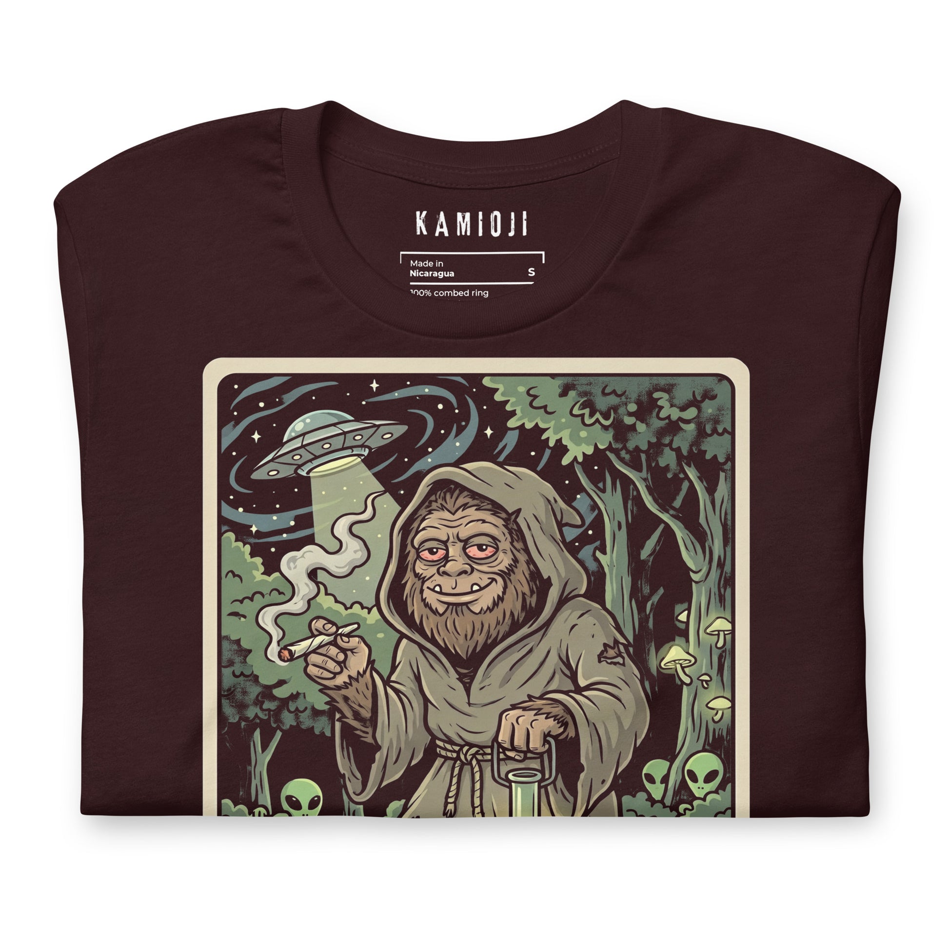 Graphic of a UFO with a light beam above a hooded Sasquatch in a forest setting from 'The Hermit' tarot card.